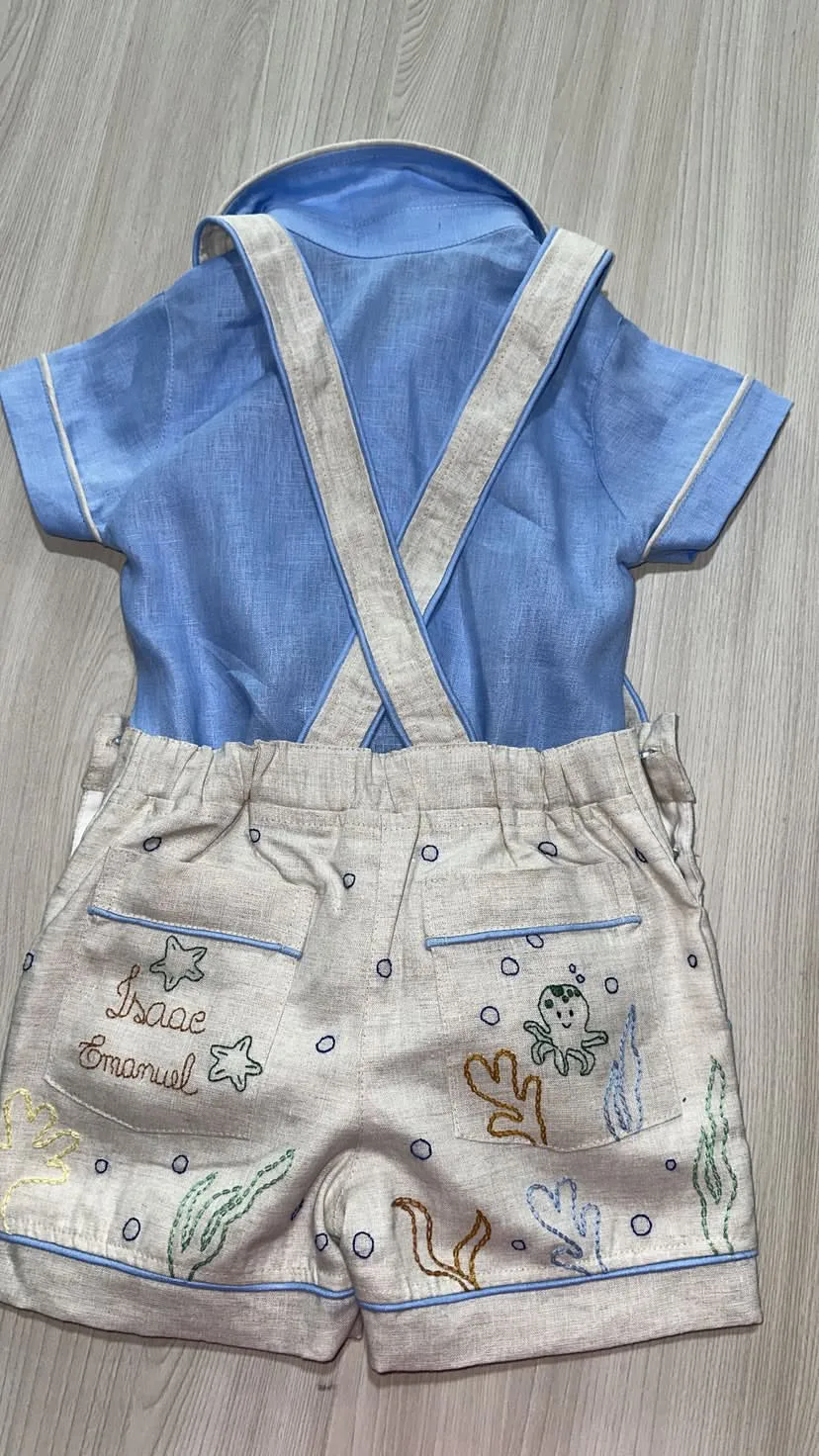 Jardineira Premium vista pelas costas mostrando alça com fivela metálica artesanal, pesponto duplo em linha contrastante e acabamento interno com viés coordenado